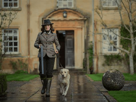 Imagen de la madre de los protagonistas de The Gentlemen demostrando que se puede ir con mucho estilo con un escopetón de caza.
